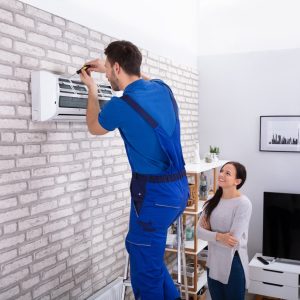 Male Technician Repairing Air Conditioner With Screwdriver